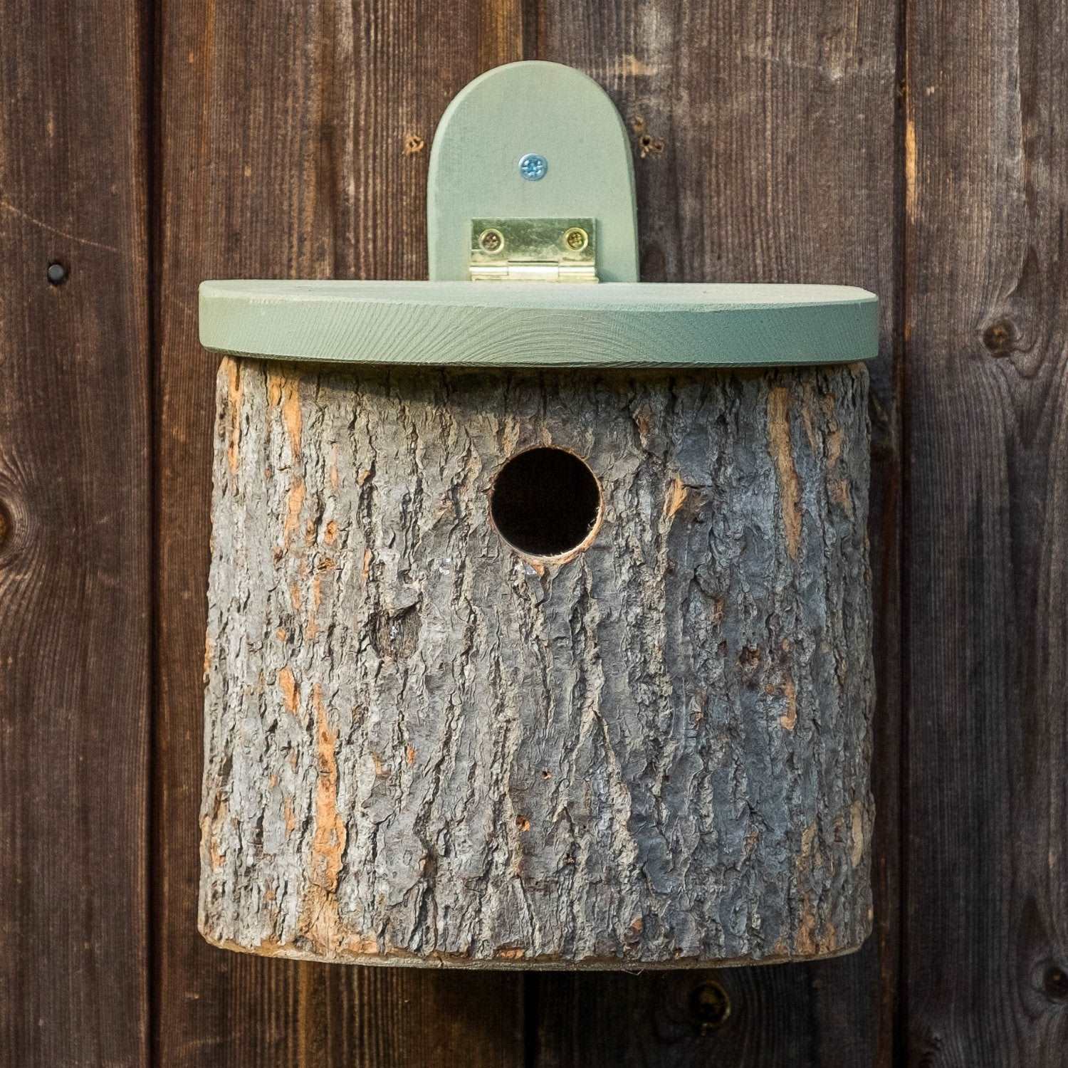 Natural Log Bird Nester (Green) - The Irish Gardener Store Natural Log Bird Nester, rustic wooden design with natural bark exterior, green-painted slanted roof, circular entrance hole for small birds, eco-friendly bird nesting box, mounted securely on a wooden surface, ideal for garden and outdoor use, wildlife-friendly habitat
