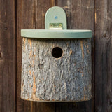 Natural Log Bird Nester (Green) - The Irish Gardener Store Natural Log Bird Nester, rustic wooden design with natural bark exterior, green-painted slanted roof, circular entrance hole for small birds, eco-friendly bird nesting box, mounted securely on a wooden surface, ideal for garden and outdoor use, wildlife-friendly habitat