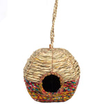 A spherical Anita Artisan Bird Nester crafted from natural woven fibers, featuring a colorful multicolored base, a round central entrance hole, and a sturdy braided hanging rope, designed as a decorative and functional shelter for small garden birds.