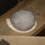 Close-up of a ceramic swallow nesting bowl mounted on a wooden base, securely attached to a wooden beam, designed to provide a safe nesting spot for swallows