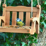 Swingseat Bird Feeder - The Irish Gardener Store natural wooden swingseat bird feeder, hanging bird feeder on ropes, rustic garden decor, wooden swing bird feeder for seeds, outdoor bird feeding station, eco-friendly bird feeder hanging in garden, bird feeder in countryside setting, handcrafted wooden swing bird feeder