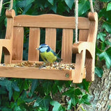 Swingseat Bird Feeder - The Irish Gardener Store natural wooden swingseat bird feeder, hanging bird feeder on ropes, rustic garden decor, wooden swing bird feeder for seeds, outdoor bird feeding station, eco-friendly bird feeder hanging in garden, bird feeder in countryside setting, handcrafted wooden swing bird feeder