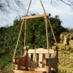 Swingseat Bird Feeder - The Irish Gardener Store natural wooden swingseat bird feeder, hanging bird feeder on ropes, rustic garden decor, wooden swing bird feeder for seeds, outdoor bird feeding station, eco-friendly bird feeder hanging in garden, bird feeder in countryside setting, handcrafted wooden swing bird feeder