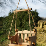 Swingseat Bird Feeder - The Irish Gardener Store natural wooden swingseat bird feeder, hanging bird feeder on ropes, rustic garden decor, wooden swing bird feeder for seeds, outdoor bird feeding station, eco-friendly bird feeder hanging in garden, bird feeder in countryside setting, handcrafted wooden swing bird feeder