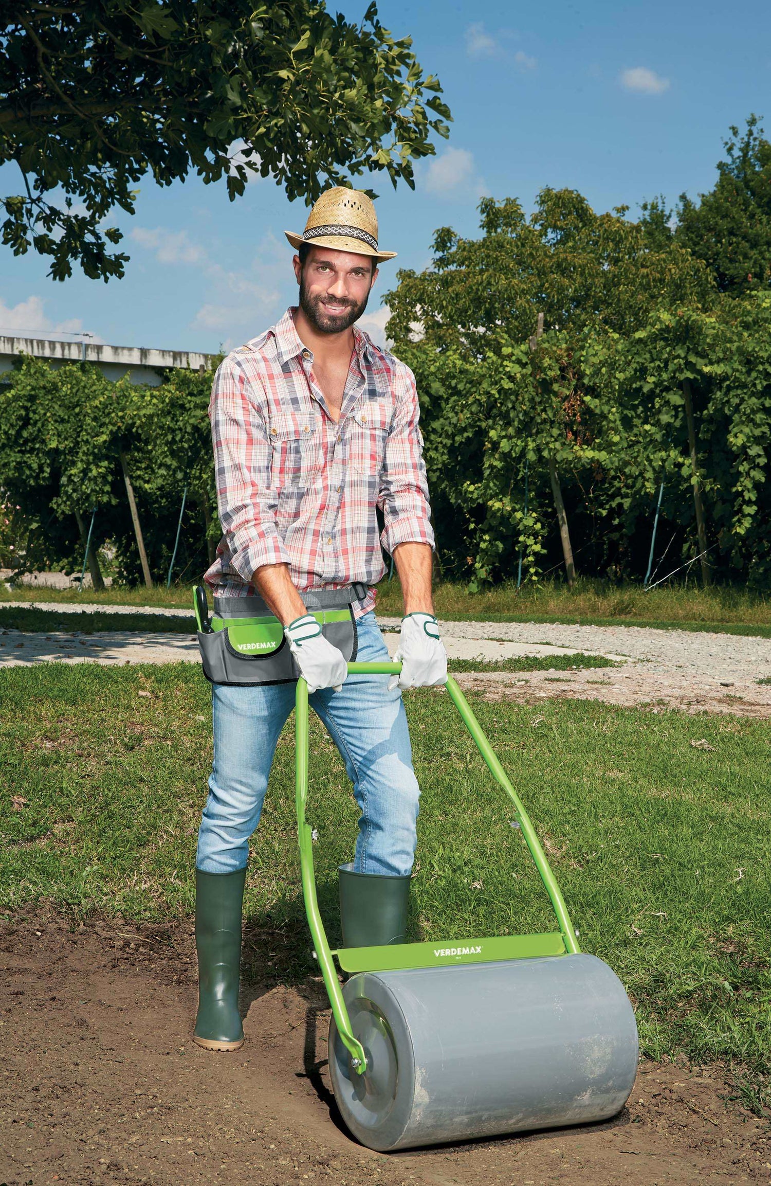 Image of the Verdemax Garden Roller, showcasing its sturdy construction and convenient handle for easy maneuverability. The roller is filled with water and shown being used to flatten and smooth out the soil in a garden bed.