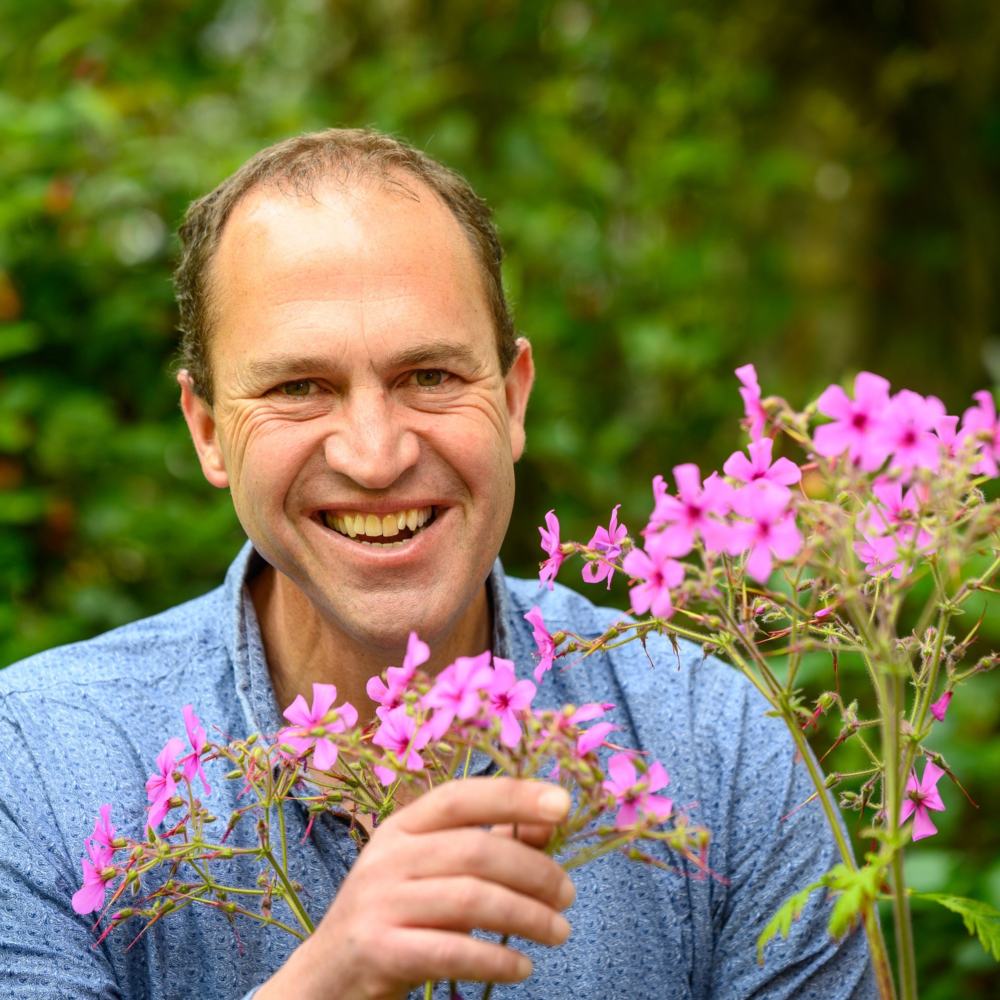 Peter Dowdall smiling in a garden setting with summer planting