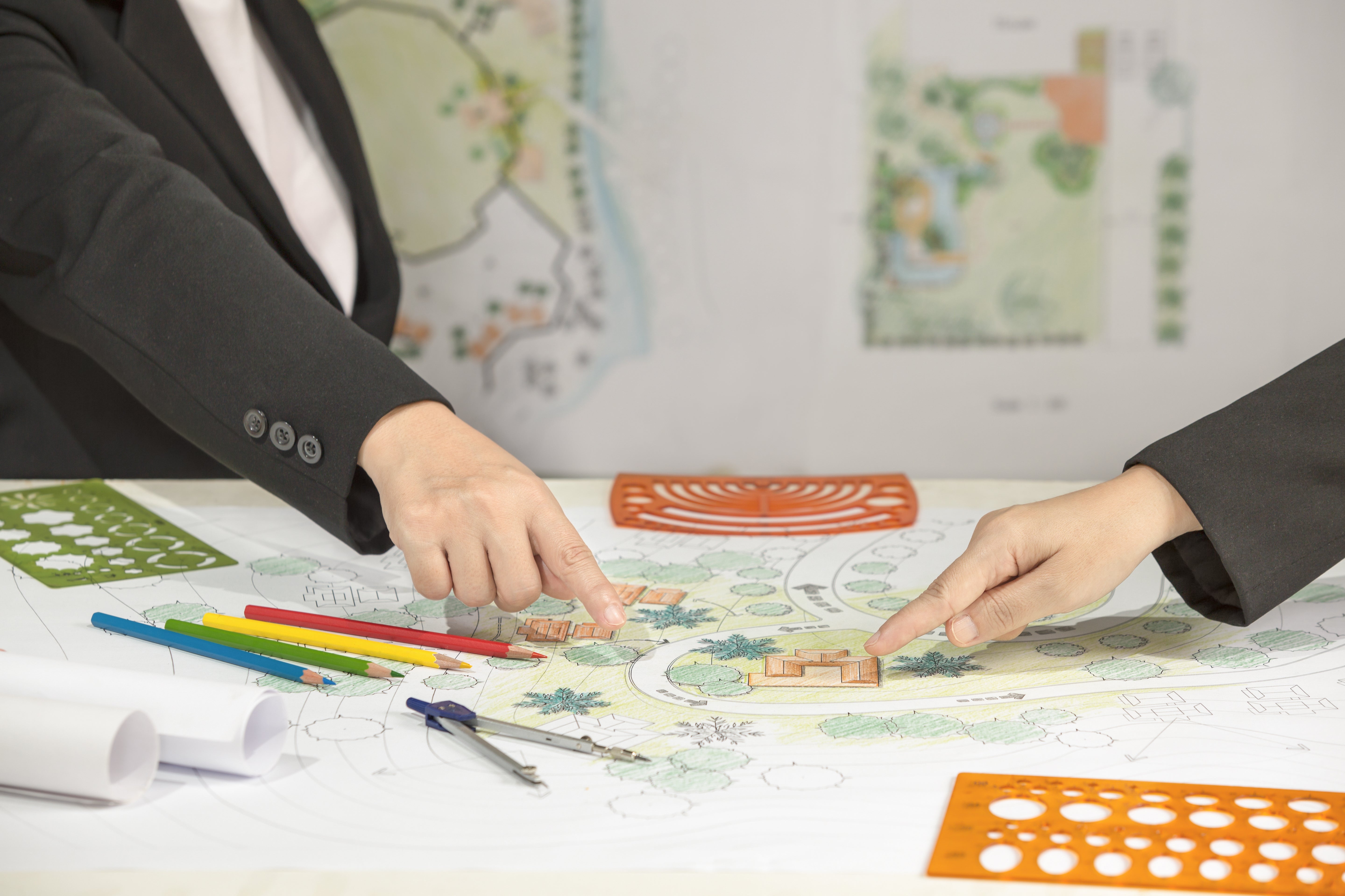 two hands pointing at a agrden design in a meeting discussing a garden design 
