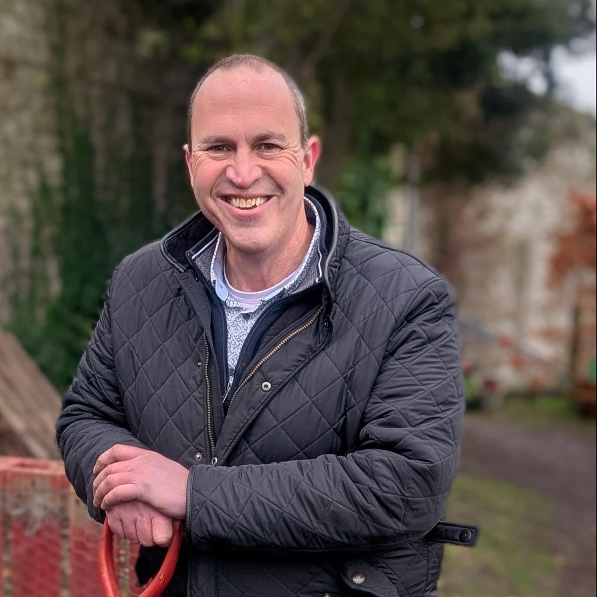 Peter Dowdall Irish Garden Designer and gardening consultant holding a shovel in an outdoor setting with a red tool chest and greenery.