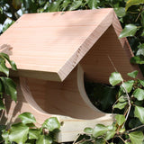 "Blackbird Nest Box, wooden open-front design, natural untreated timber, nestled among green ivy leaves, sloped roof for weather protection, eco-friendly bird nesting box, ideal for blackbirds and garden wildlife"