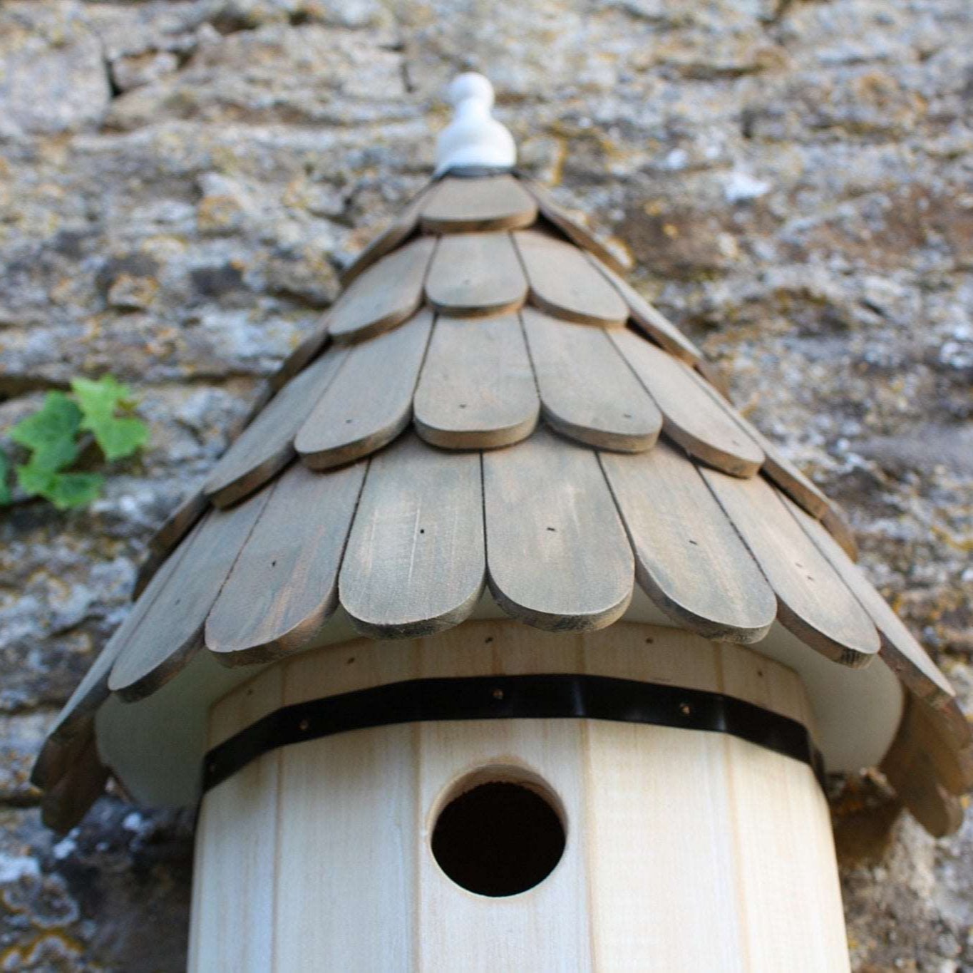 Dovecote Nest Box - The Irish Gardener Store Wooden dovecote nest box, featuring a traditional round design, scalloped wooden roof with natural finish, small circular entry hole, decorative white finial on top, elegant and rustic birdhouse design