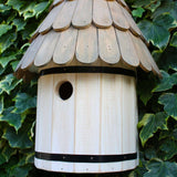 Dovecote Nest Box - The Irish Gardener Store Wooden dovecote nest box, featuring a traditional round design, scalloped wooden roof with natural finish, small circular entry hole, decorative white finial on top, mounted against a backdrop of lush green ivy, elegant and rustic birdhouse design