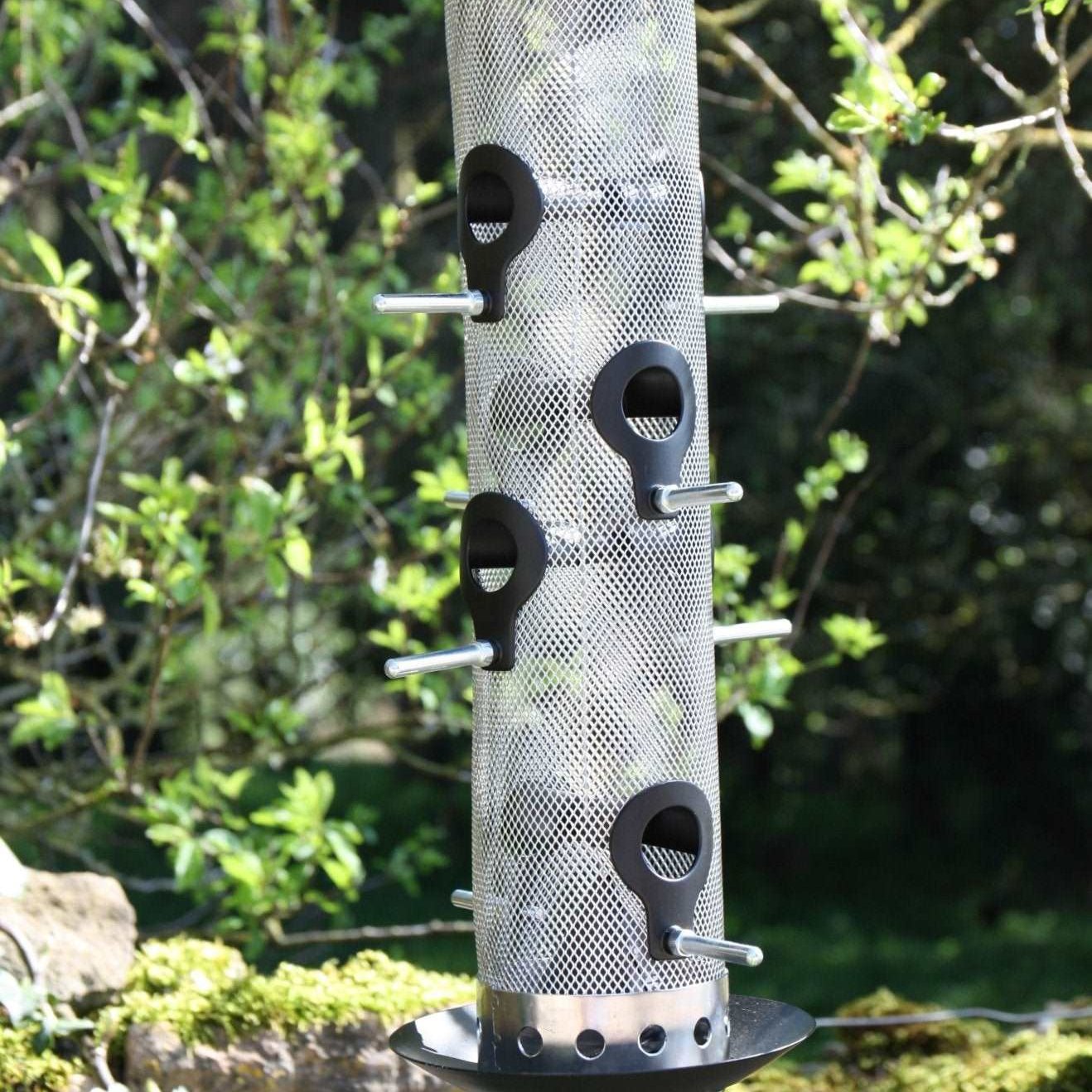 Giant Bird Seed Feeder - The Irish Gardener Store Giant bird seed feeder, tall cylindrical design, metal mesh body, black weather-resistant top and base, multiple feeding ports with perch attachments, hanging wire for easy installation, ideal for attracting multiple bird species