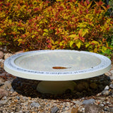 Shenstone Theatre Bird Bath and Drinker - The Irish Gardener Store shenstone Theatre Bird Bath and Drinker on a stone pedestal, , elegant circular design, smooth cream-colored surface, engraved rim detailing, outdoor garden setting, bird-friendly garden feature.